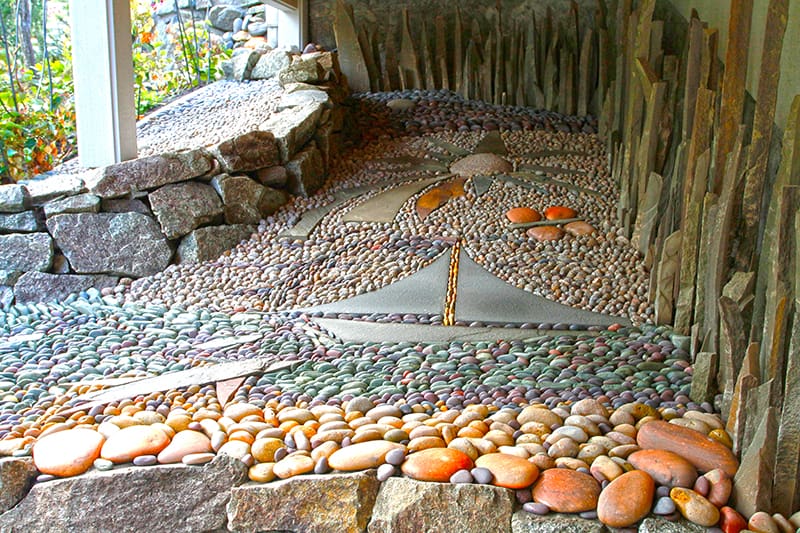 Pebble stone mosaic. A garden accent lawn installation with stone retaining wall